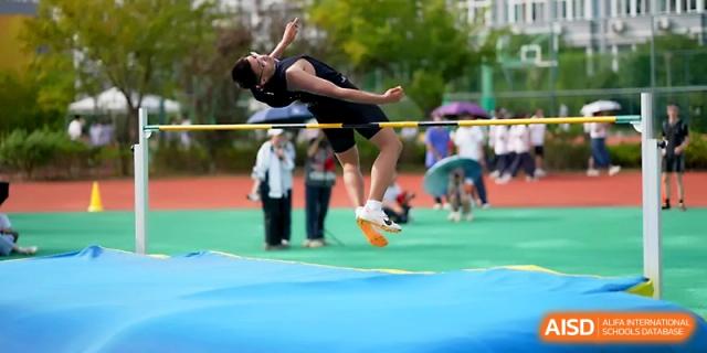 A student athlete performs a high jump, captured mid-air as he clears the horizontal bar at Ningbo Beilun High School.