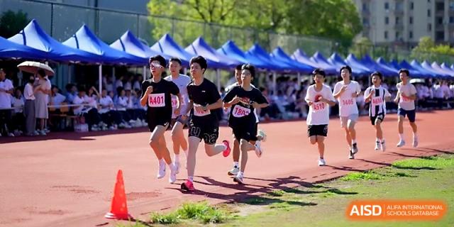 Four female athletes participate in a relay race, maintaining high speed on the red track at Ningbo Beilun High School.