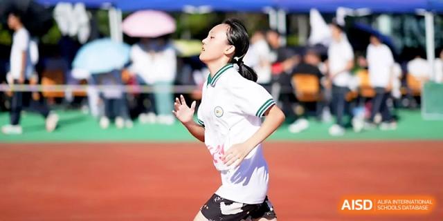 A female student sprints with effort during a track event under the bright sun at Ningbo Beilun High School.