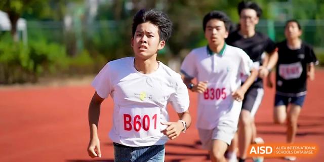 A male student in a white athletic shirt runs with focus during a competitive track race at Ningbo Beilun High School.