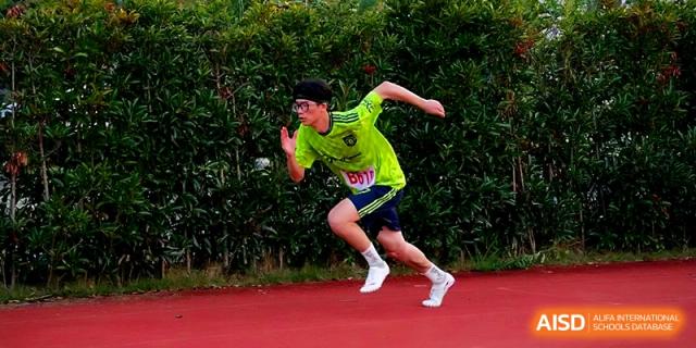 A male student in a bright green shirt sprints powerfully during a track competition at Ningbo Beilun High School.