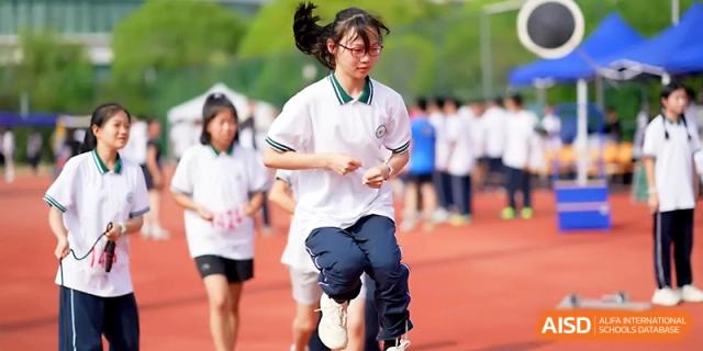 A female student athlete smiles while running a race on the school's outdoor track at Ningbo Beilun High School.