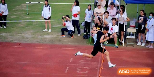 A student sprints toward the finish line during a track event as classmates watch at Ningbo Beilun High School.