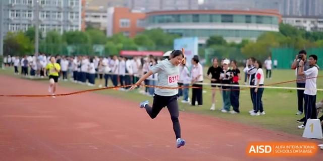 A female athlete sprints toward the camera during a competitive track and field event at Ningbo Beilun High School.