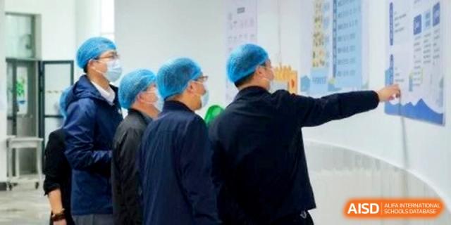 Staff members in protective gear inspect kitchen facilities to ensure food safety standards at Ningbo Beilun High School.