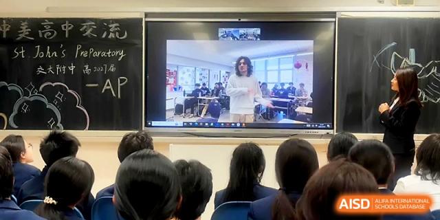 Students in a classroom watch a video call from an international speaker displayed on a large screen at The High School Affiliated to Xi_an Jiaotong University.