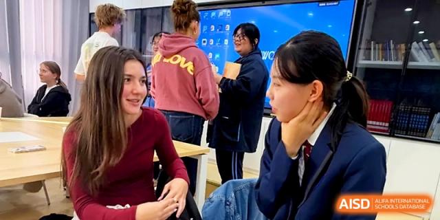 Local and international students engage in a friendly conversation and cultural exchange inside a classroom at The High School Affiliated to Xi_an Jiaotong University.