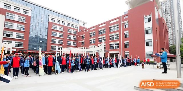 A wide outdoor shot of the red brick school campus with students gathered in the courtyard for an event at The High School Affiliated to Xi_an Jiaotong University.