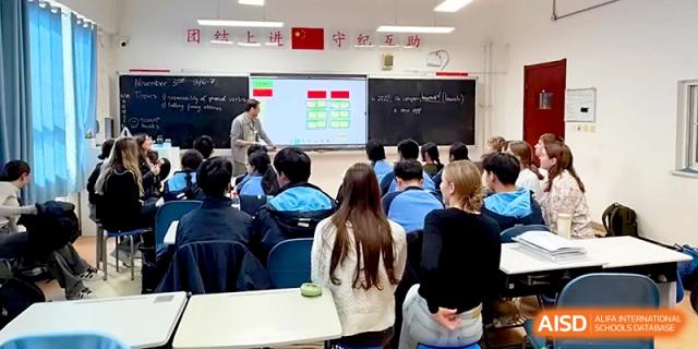 Students listen to a teacher explaining a lesson using a digital screen in a well-equipped modern classroom at The High School Affiliated to Xi_an Jiaotong University.