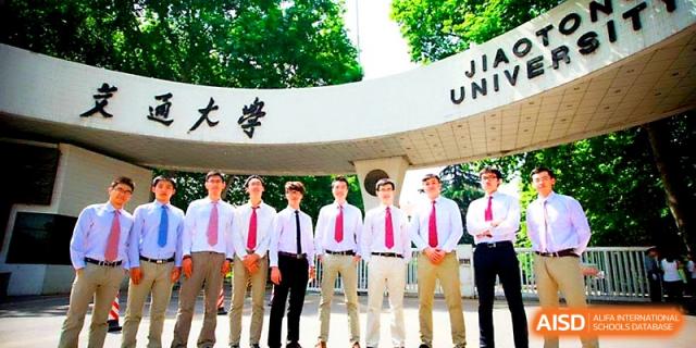 Six young men in white shirts and colorful ties pose together under the school's stone entrance archway at The High School Affiliated to Xi_an Jiaotong University.