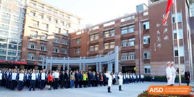 A large group of faculty and students stands in formation during an outdoor ceremony on the school grounds at The High School Affiliated to Xi_an Jiaotong University.