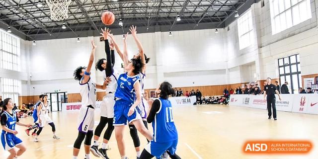 Female basketball players in blue jerseys compete for a rebound during a high-energy game in the school gymnasium at The High School Affiliated to Xi_an Jiaotong University.