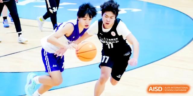 Two basketball players in opposing jerseys face off as one dribbles the ball down the court during a match at The High School Affiliated to Xi_an Jiaotong University.