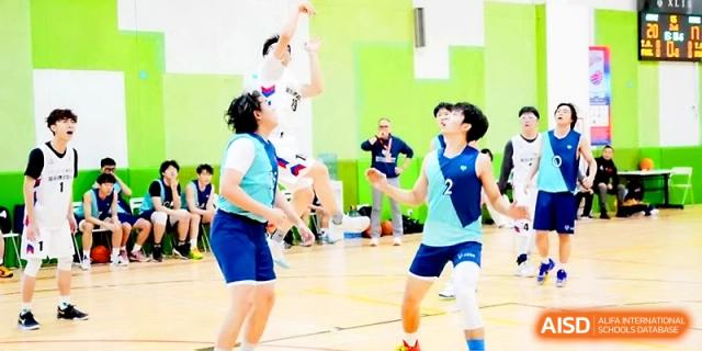 A basketball player in a blue uniform prepares to catch a pass during a fast-paced game in the indoor gymnasium at The High School Affiliated to Xi_an Jiaotong University.
