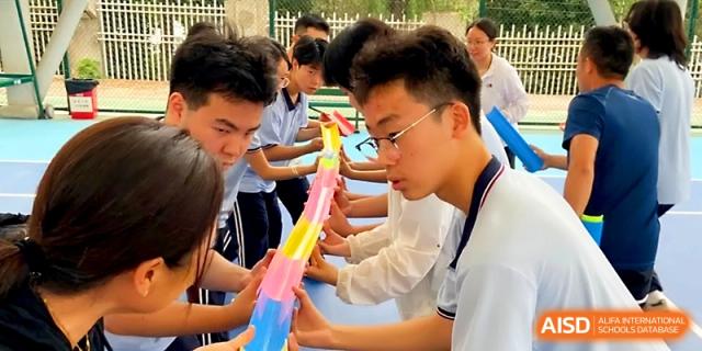Close-up of students working together to align colorful plastic tracks for a ball-drop team challenge at The High School Affiliated to Xi_an Jiaotong University.