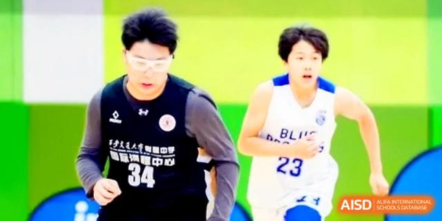 Two basketball players focus on the game as they move across the court during a competitive inter-school match at The High School Affiliated to Xi_an Jiaotong University.