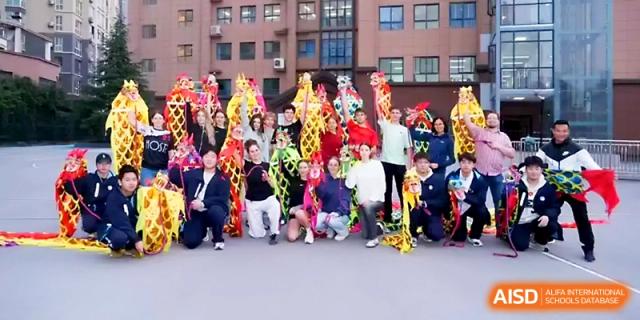 Students and performers pose with colorful, long dragon dance props after a vibrant cultural performance at The High School Affiliated to Xi_an Jiaotong University.