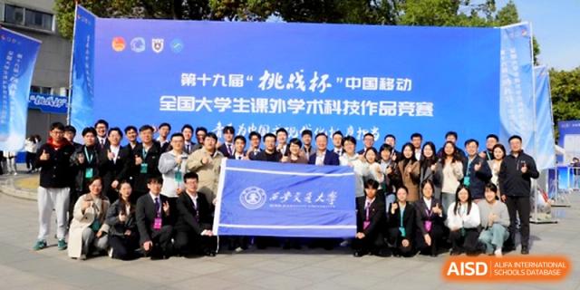 A large group of students and faculty members pose proudly behind a blue school banner during an official event at The High School Affiliated to Xi_an Jiaotong University.