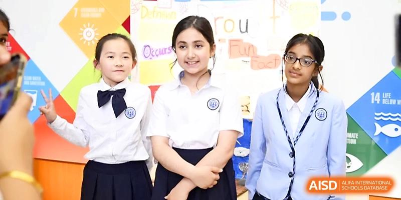 Three smiling female students in school uniforms stand together during a presentation event at Wahaha International School.