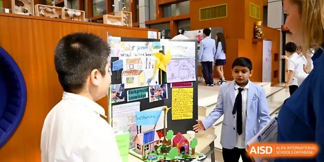 A student presents a detailed science fair project featuring a model house and solar panels at Wahaha International School.