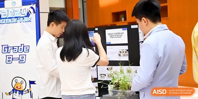 Students gather around a science exhibit featuring live plants and informational posters at Wahaha International School.