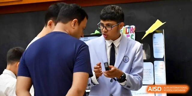 A student in a blazer discusses a project titled "Healthy Eyes" with an adult visitor at Wahaha International School.