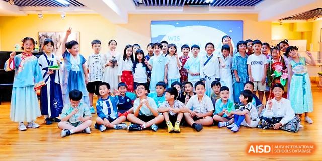 A large group of primary students sits and stands together for a cheerful group photo at Wahaha International School.
