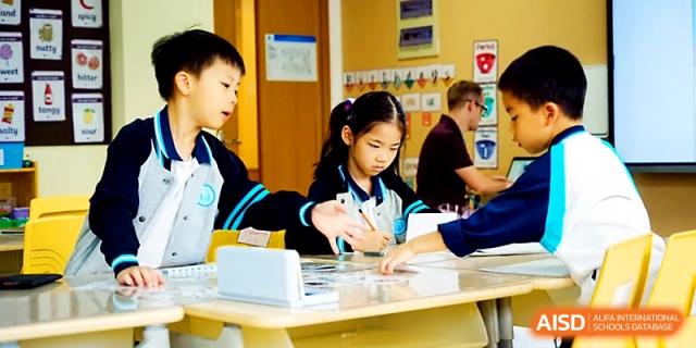 Two students work collaboratively on a tabletop project in a bright classroom at Wahaha International School.