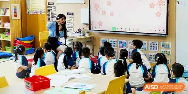 Students sit at their desks focused on a presentation shown on a large screen at Wahaha International School.