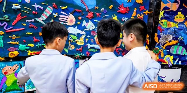 Students admire a vibrant, blue-themed underwater art display on a school hallway wall at Wahaha International School.