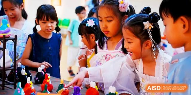 Young students smile and interact with colorful crafts during a festive school day at Wahaha International School.