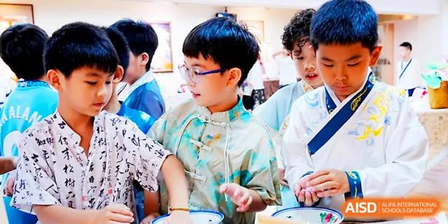 Students in patterned shirts focus on a collaborative task during a classroom project at Wahaha International School.