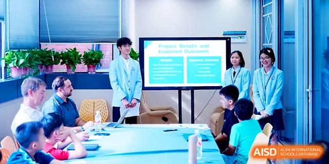 A student presents "Project Details" using a large television screen in a modern room at Wahaha International School.