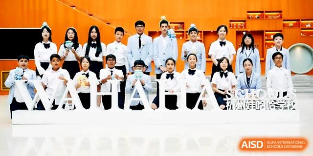 A formal group of students in white shirts and bow ties poses behind a school sign at Wahaha International School.