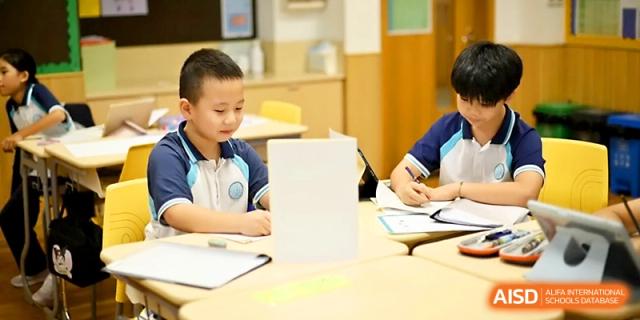 Young students focus on their desk work and drawing during a quiet classroom activity at Wahaha International School.