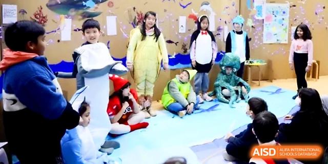 Students dressed in colorful animal and nature costumes perform in a school play at Wahaha International School.