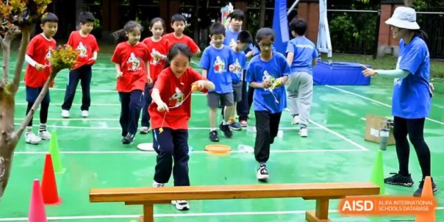 Students in red and blue shirts participate in an outdoor balance and coordination drill at Wahaha International School.
