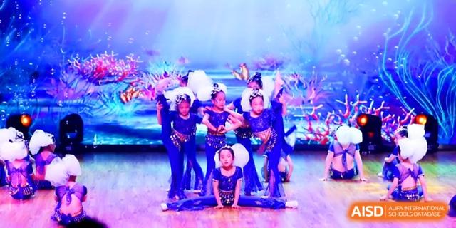 A cheerleading or dance squad performs an impressive pyramid formation on stage at Wahaha International School.