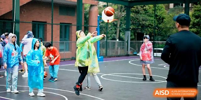 A student practices a basketball shot on the outdoor court during a sports session at Wahaha International School.