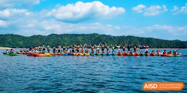 A group of students enjoys a rowing or boating activity on a scenic lake during a field trip at Wahaha International School.
