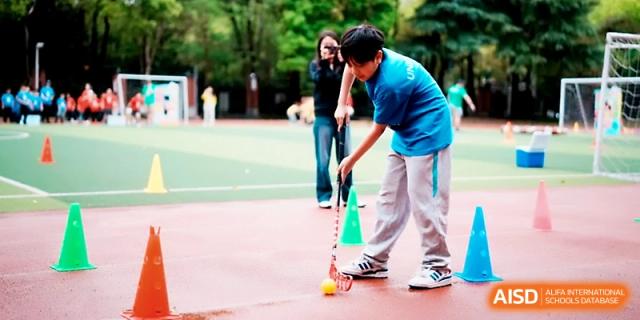 A student practices field hockey or floorball skills during an outdoor physical education class at Wahaha International School.