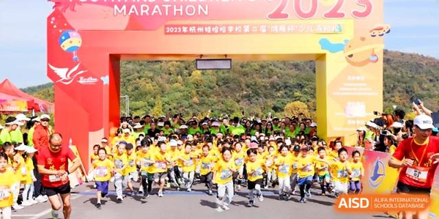 A large crowd of students in yellow shirts gathers at the starting line of a school marathon at Wahaha International School.