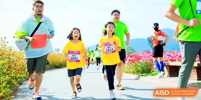 Students and a parent participate in a community fun run or marathon event at Wahaha International School.
