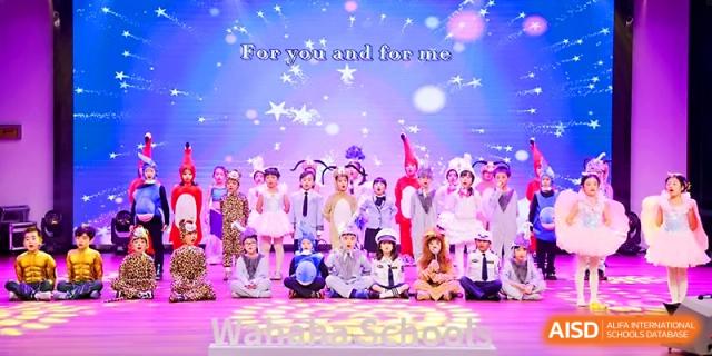 Children in formal wear and costumes perform a musical number on a purple-lit stage at Wahaha International School.