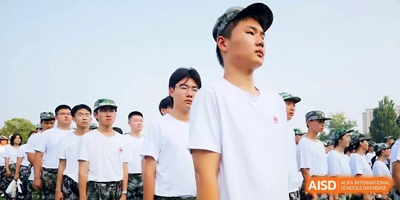 A group of male students in white t-shirts and caps stand in an orderly line outdoors, looking forward with focus at WeiFang No.1 Middle School.