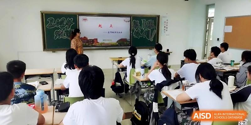 A teacher stands at the front of a classroom by a chalkboard, addressing a group of students seated at their desks at WeiFang No.1 Middle School.