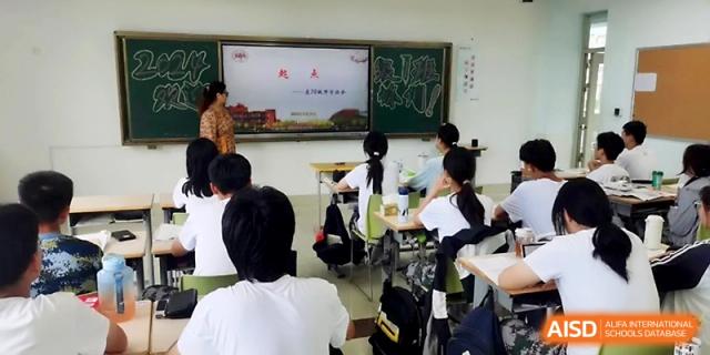 A teacher stands at the front of a classroom by a chalkboard, addressing a group of students seated at their desks at WeiFang No.1 Middle School.