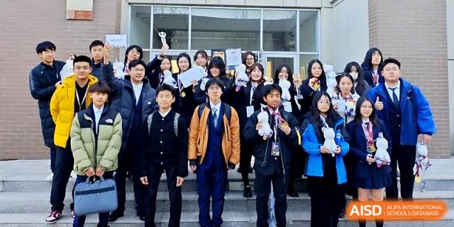 A large group of students in blue school uniforms stand together outside a building, posing for a commemorative photo at WeiFang No.1 Middle School.