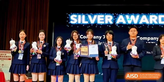 Four female students in school uniforms proudly hold awards and stuffed mascots on a stage during a ceremony at WeiFang No.1 Middle School.