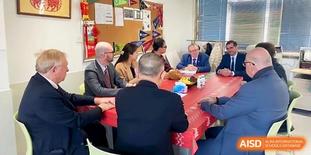 Educators and staff sit around a red table in a decorated room for a collaborative meeting or discussion at WeiFang No.1 Middle School.
